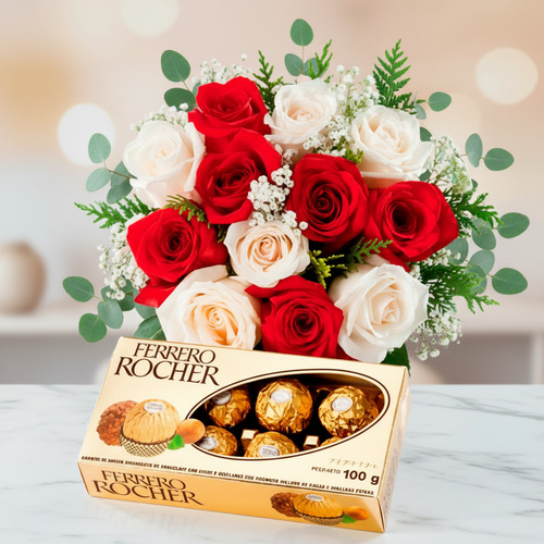Ramo de rosas rojas y blancas con caja de chocolates Ferrero Rocher Arreglo floral de rosas rojas y blancas con follaje verde acompañado de una caja de chocolates Ferrero Rocher sobre superficie de mármol