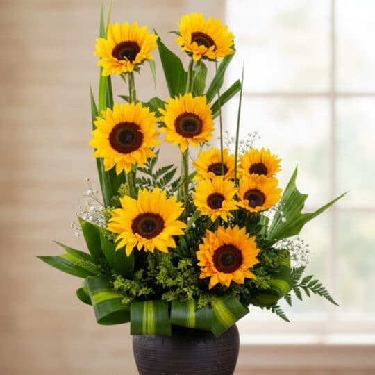 Arreglo floral GIULIANA con girasoles radiantes en un jarrón oscuro, ideal para ecommerce de floristería, con fondo elegante