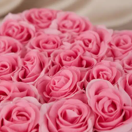 Primer plano extremo de un arreglo floral de rosas rosadas en forma de corazón, con gotas de rocío sutiles y textura hiperrea
