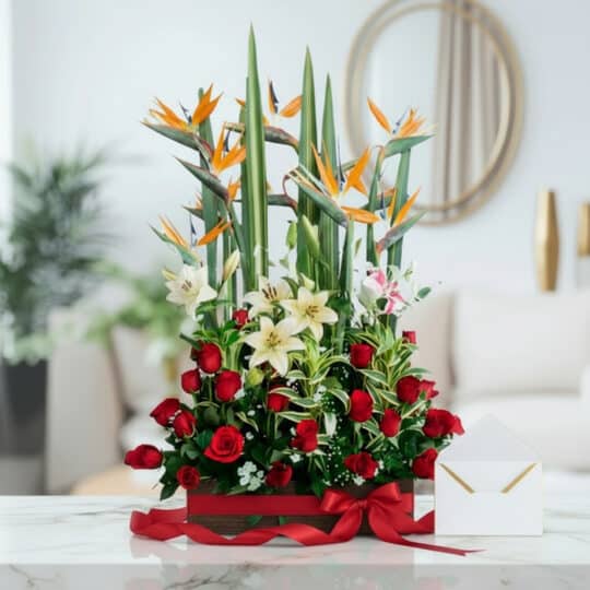 Arreglo floral 'Siempre Juntos' con lirios blancos, rosas rojas y aves del paraíso, sobre mármol, listo para regalo.