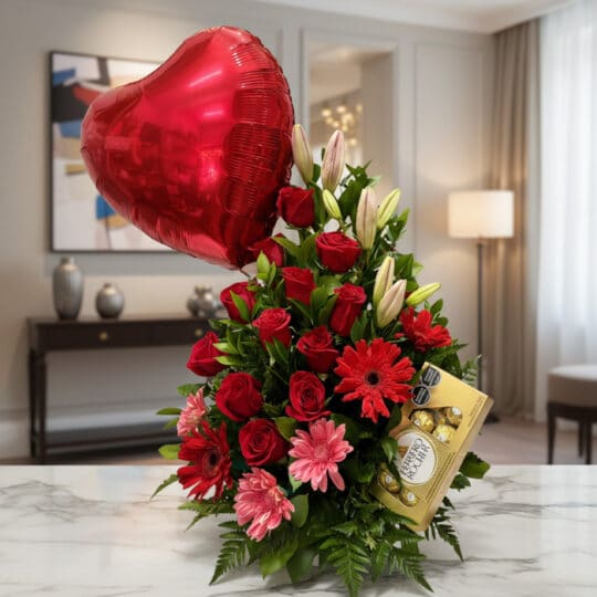 Arreglo floral 'Te Amo' con rosas rojas, lirios blancos, gerberas rosadas y rojas, follaje verde, un globo de corazón rojo y