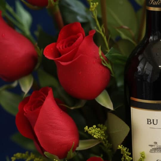 Primer plano extremo de rosas rojas frescas con gotas de rocío y una botella de vino, resaltando la textura y los colores vib