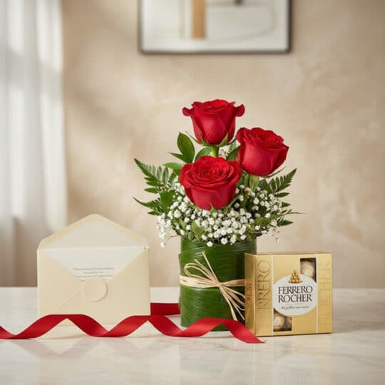 Solitario de tres rosas rojas frescas en jarrón de hojas, acompañado de caja de bombones Ferrero Rocher, tarjeta de regalo y